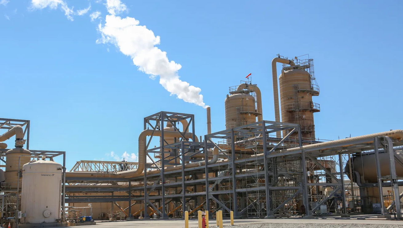 Power plant with steam coming from stack against blue sky