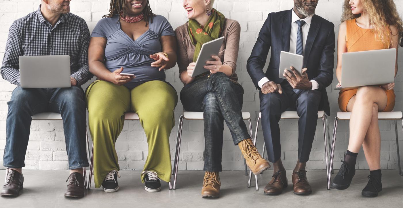 Stock photo of a diverse group of people sharing information on their devices.