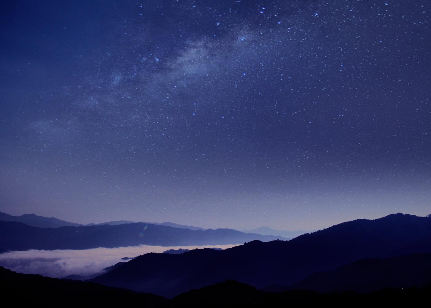 Silhouette of mountains against blue night sky with stars