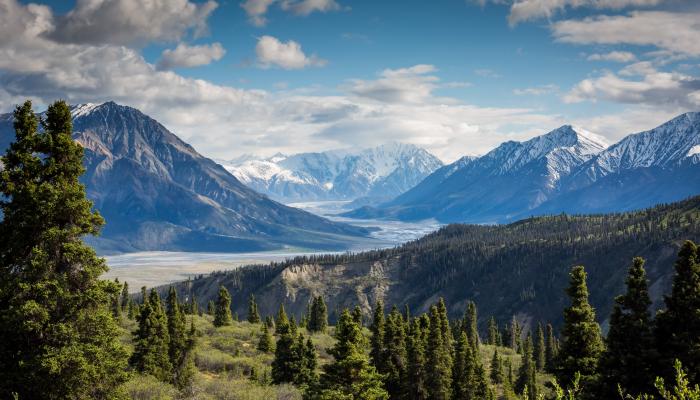 A mountainous region with multiple peaks and valleys, lush greenery, and blue skies