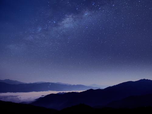 Silhouette of mountains against blue night sky with stars