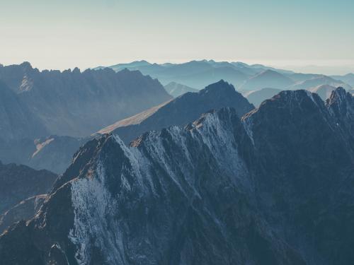 Steep, snowy mountains with a hazy blue sky above them.