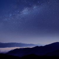 Silhouette of mountains against blue night sky with stars